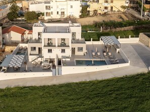 Un bâtiment moderne à deux étages doté d’une piscine sur le toit, de nombreux balcons et d’un vaste espace extérieur aménagé pour se détendre.