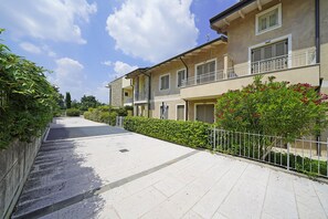 A residential street with a row of two-story houses, a paved sidewalk, and a metal fence. - Residence Quadrivium 151 by Wonderful Italy (Castelnuovo del Garda)