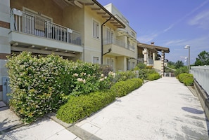 A multi-story residential building with balconies, a paved pathway, and well-maintained greenery. - Residence Quadrivium 151 by Wonderful Italy (Castelnuovo del Garda)