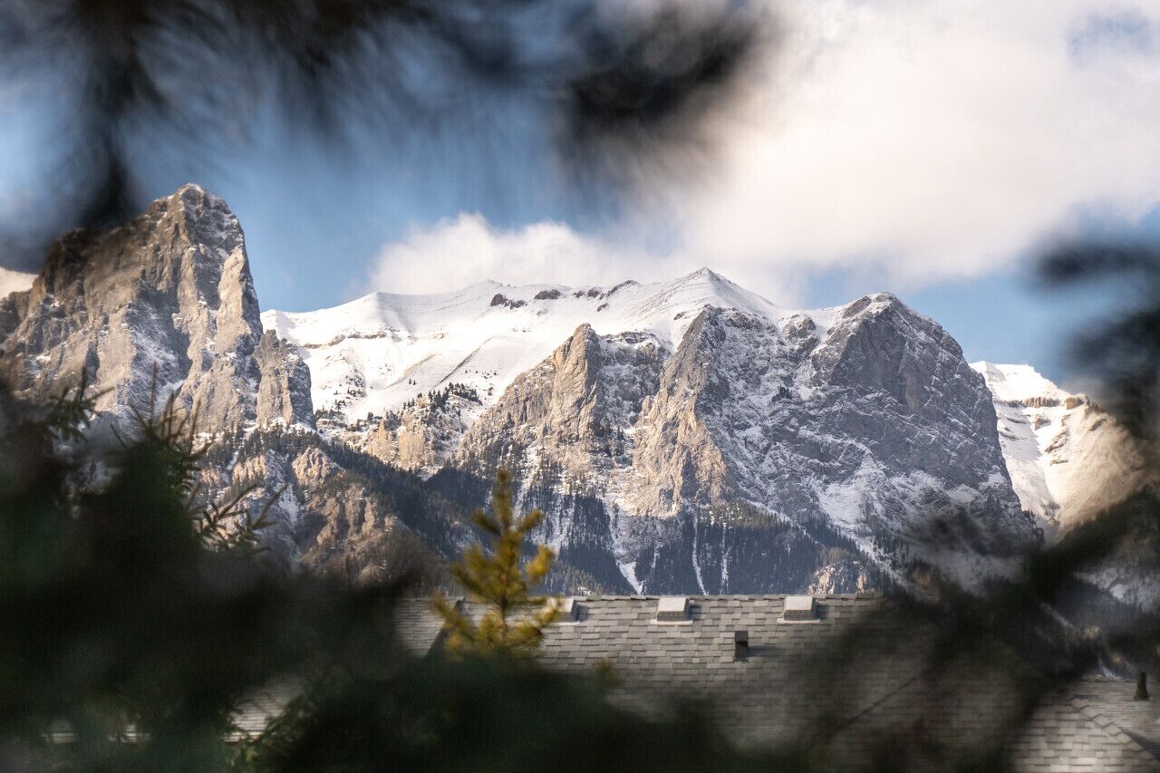 Berglandschap met besneeuwde toppen en een stenen gebouw op de voorgrond.