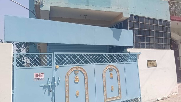 A blue metal gate with a padlock, a sign reading "TO-LET 971415062", and a plaque with text. - Madhu Vatika Homestay By GRB (Patna)