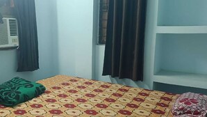 A room with a bed, a wall-mounted air conditioner, and a window with curtains. - Madhu Vatika Homestay By GRB (Patna)