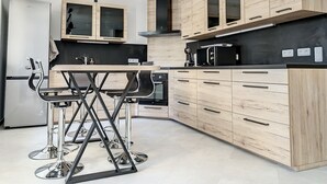 Une cuisine moderne avec des meubles en bois, un plan de travail noir et des appareils électroménagers en acier inoxydable.