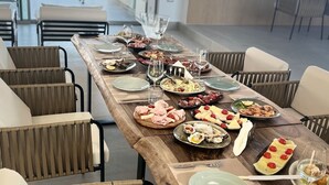 A long dining table with various dishes and glasses, surrounded by chairs. - Luxury Rooftop Suites by Blumont (Rrashbull)