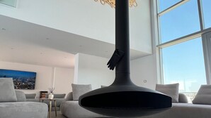 A modern living room with a large black fireplace, a sofa, and a painting on the wall. - Luxury Rooftop Suites by Blumont (Rrashbull)
