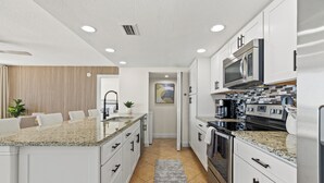 Una cocina moderna con armarios blancos, electrodomésticos de acero inoxidable y encimera de granito.