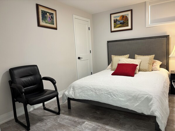 Un dormitorio con una cama, una silla y dos cuadros en la pared.
