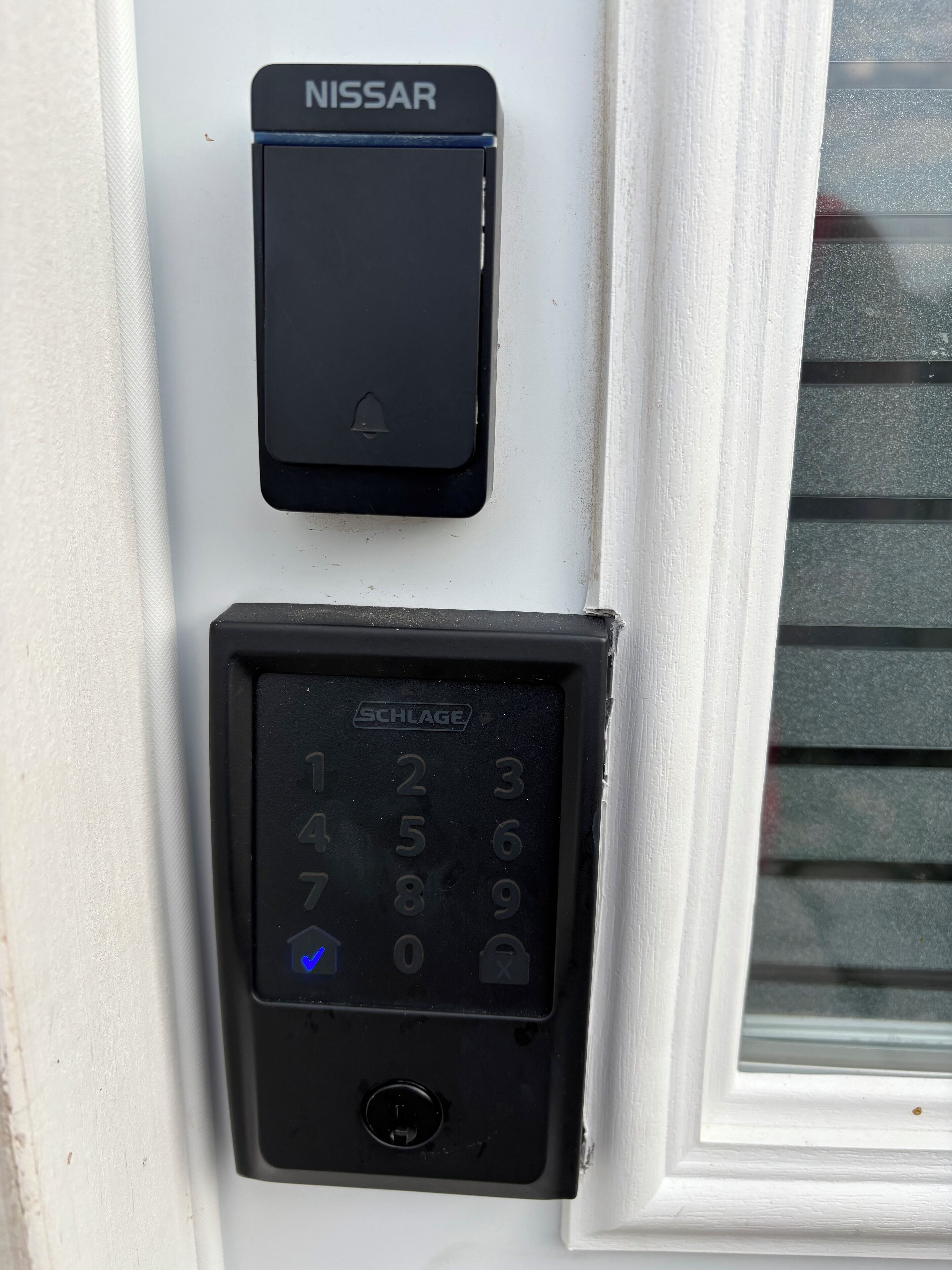 A doorbell with a numeric keypad and a push button, labeled 'NISSAR' and 'SCHLAGE'.