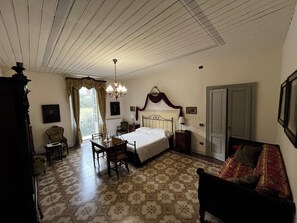 Un dormitorio con cama, una silla, una mesa, una araña y una puerta.