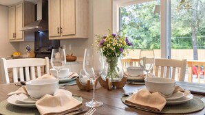 A dining table set with white bowls, napkins, and wine glasses, with a vase of flowers in the center. - The Riverhead | Springs • Pavilion • Grill (Fort White)