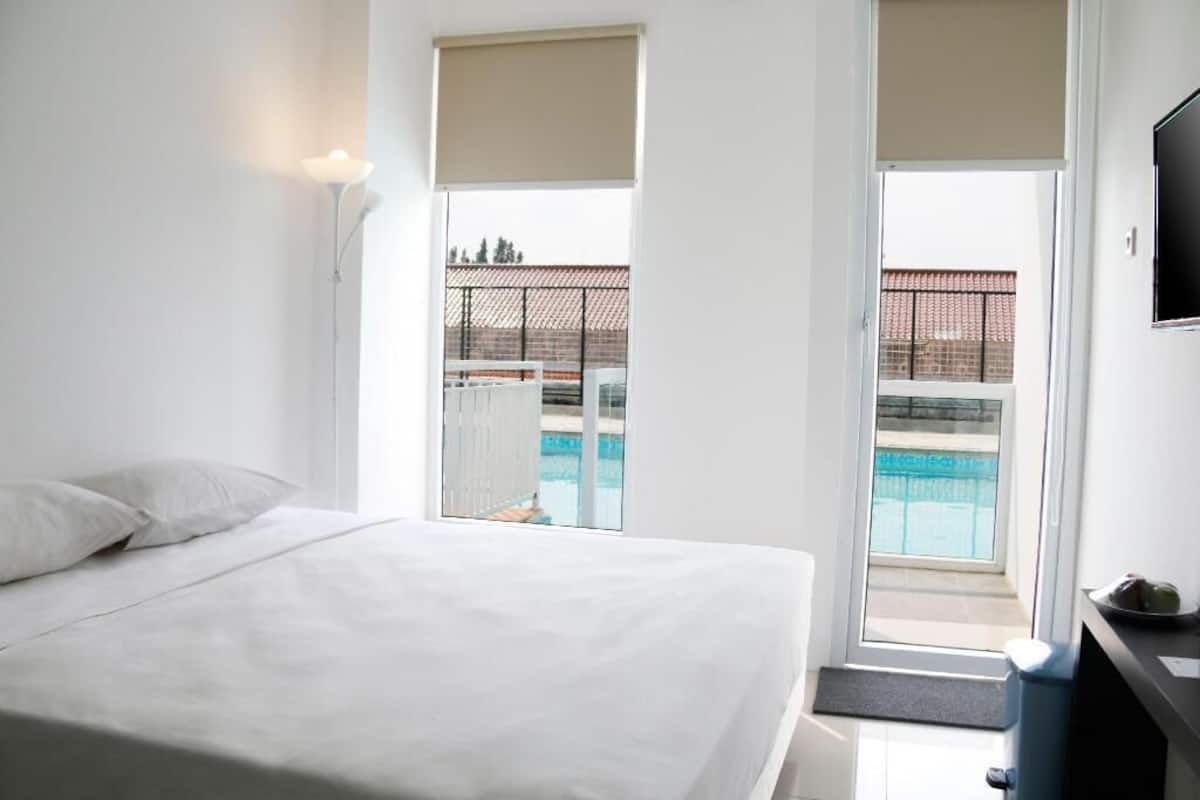 Ein Hotelzimmer mit Bett, Schreibtisch und Blick auf einen Swimmingpool.