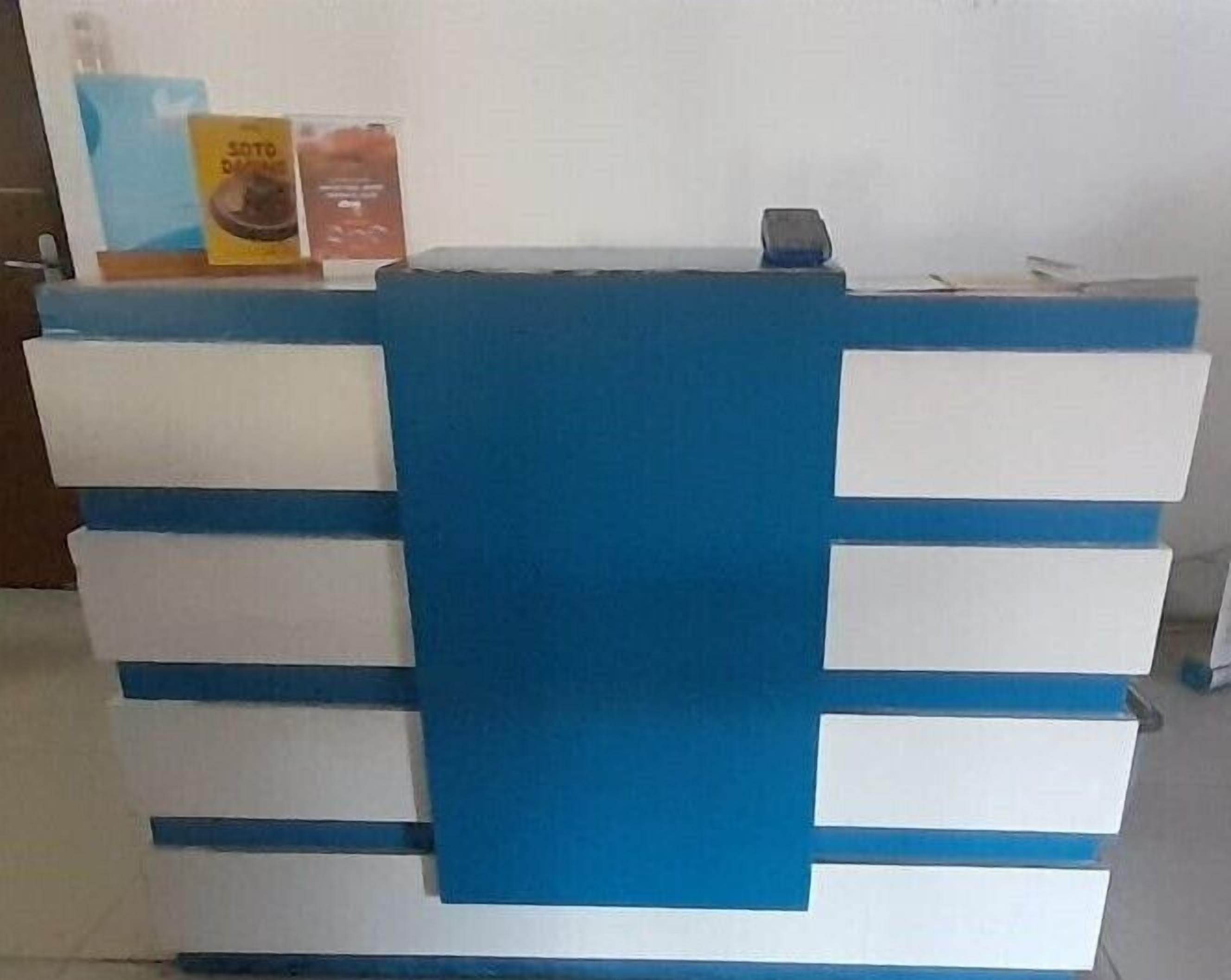 Bancada de recepção com esquema de cores azul e branco, destacando um painel azul central e gavetas brancas.