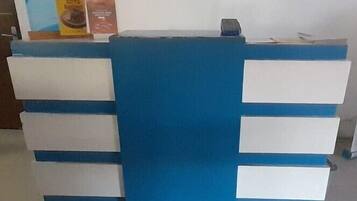 Bancada de recepção com esquema de cores azul e branco, destacando um painel azul central e gavetas brancas.