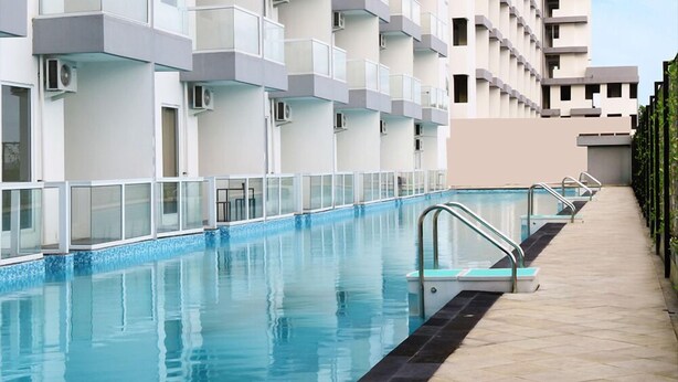 En swimmingpool ved siden af en moderne bygning med altaner og ventilationsanlæg.