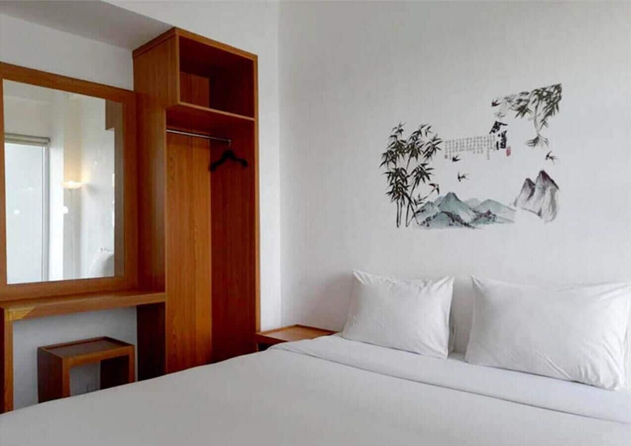 A hotel room with a bed, a wooden wardrobe, and a wall with a nature-themed mural.