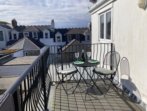 A balcony with a table and chairs, overlooking a row of houses. - Flat 4, 10 Porthminster Terr Sleeps 4, 2 bedrooms, 2 bathrooms, WiFi and parking (St Ives)