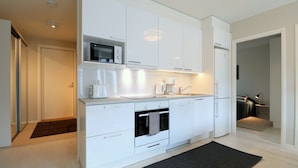 A modern kitchen with white cabinetry, a built-in oven, a microwave, and a coffee maker. - Forenom Serviced Apartments Espoo Nupuri (Espoo)