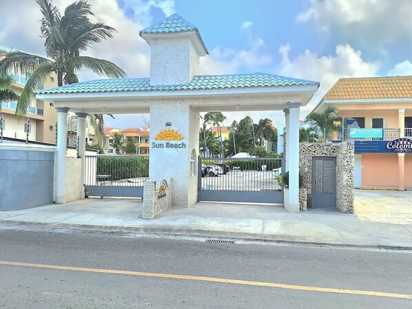 A covered entrance to a residential area named Sun Beach, featuring a gated driveway and a signboard.