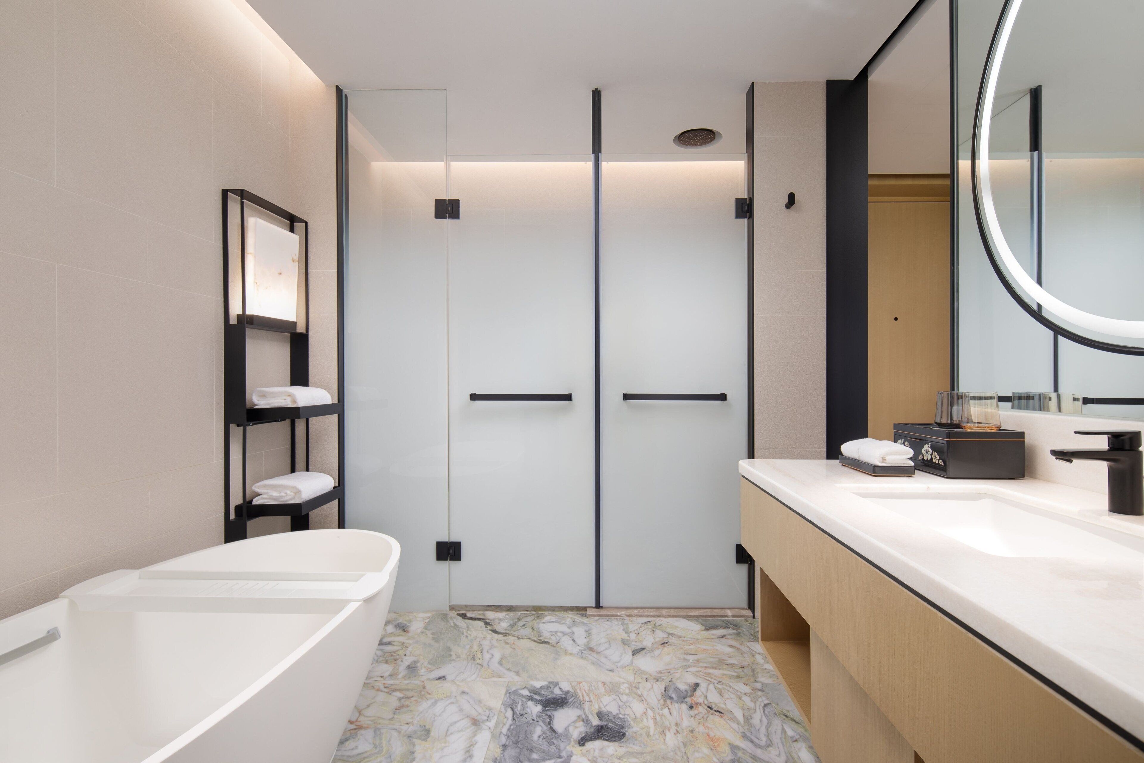 Un baño moderno con una bañera blanca, un tocador con espejo y suelo de mármol.