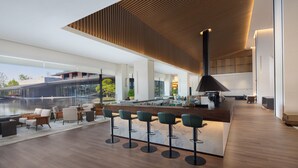 A modern bar area with a wooden ceiling, a long counter, and multiple bar stools. - Courtyard by Marriott Changzhou China (Changzhou)