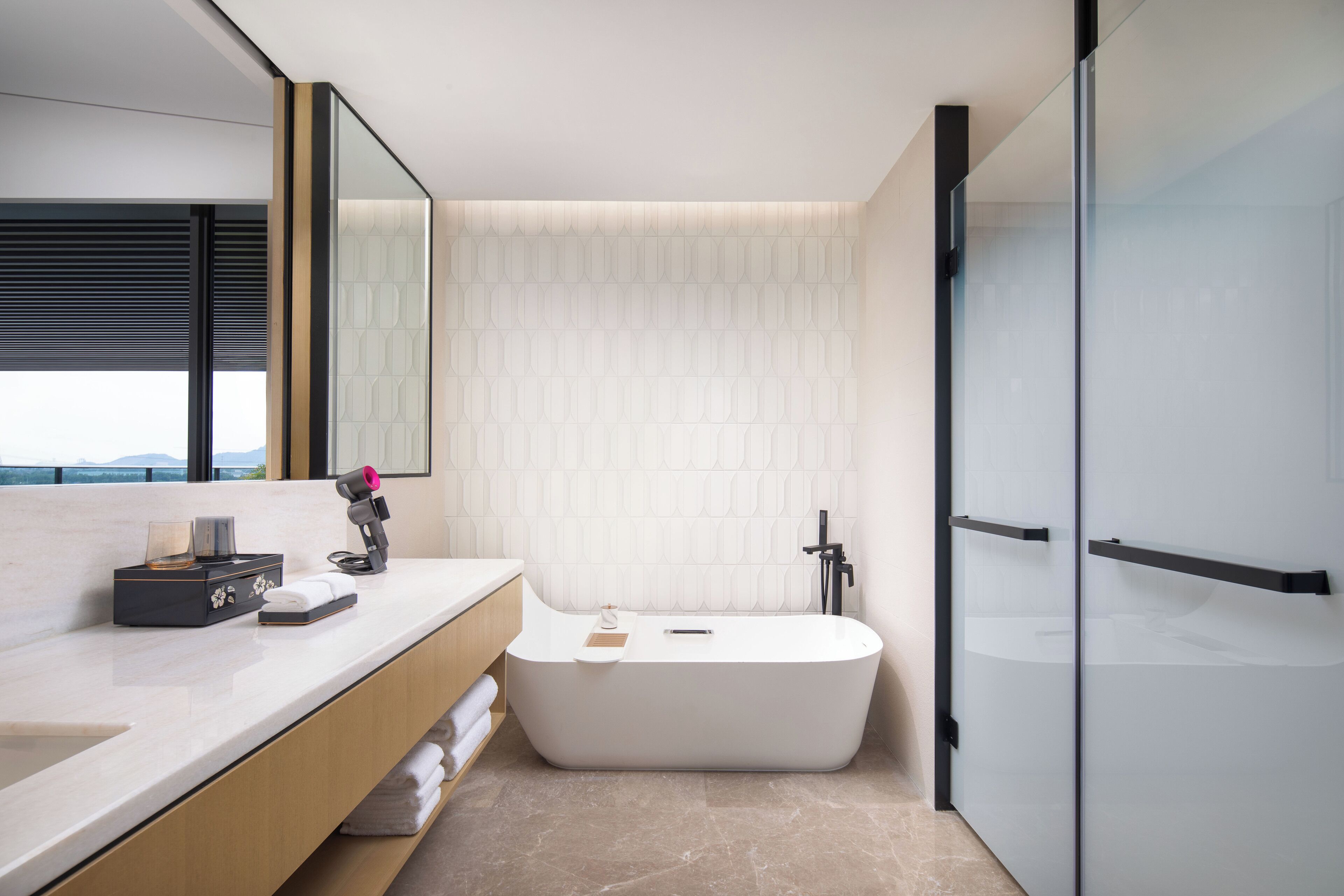 Een moderne badkamer met een vrijstaand bad, een wastafel met spiegel en een douchecabine van glas.