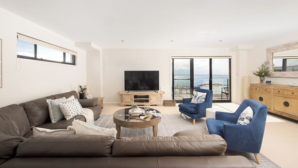 A modern living room with a sofa, armchairs, a coffee table, and a TV.