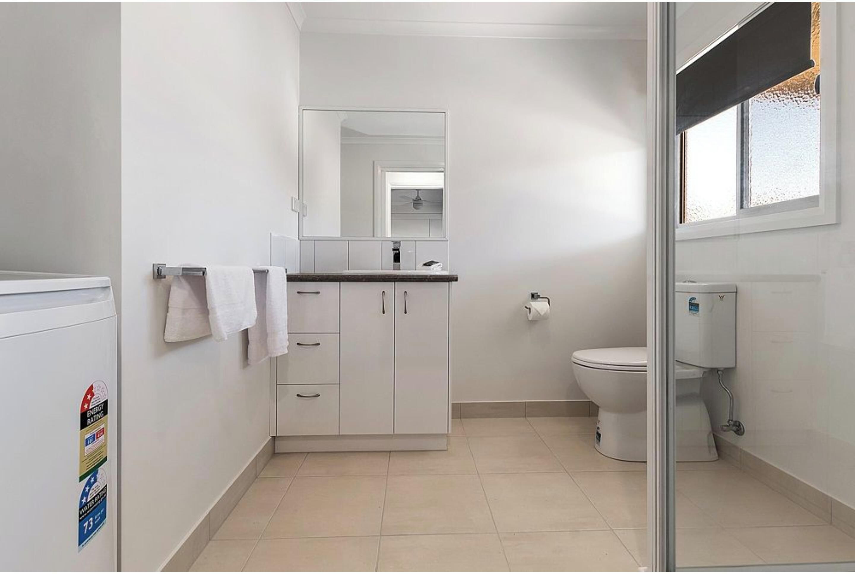 Un baño con inodoro, lavabo con espejo y un armario.