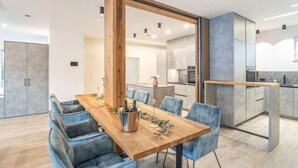 A modern dining area with a wooden table, blue upholstered chairs, and a metal wine bucket. - Penthäuser -Lorenzerhof Sauna (Murau)
