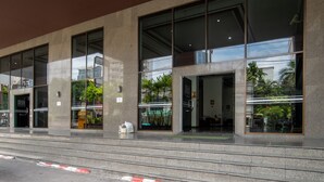 Un bâtiment moderne doté de grandes fenêtres en verre, d’une façade en béton et d’un escalier menant à l’entrée.