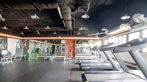 Une salle de sport équipée de tapis de course, d’appareils de musculation et d’un mur recouvert de miroirs.