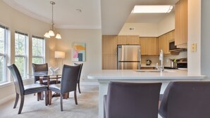 Une cuisine moderne dotée d’un réfrigérateur en acier inoxydable, de meubles en bois et d’un plan de travail blanc.