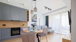 Una cocina moderna con armarios grises, encimera de madera y una zona de comedor con una mesa redonda y sillas.