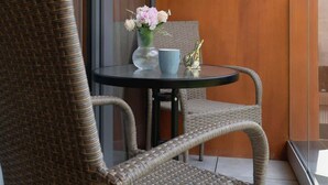 Una silla de mimbre y una mesa en un balcón con vista a un edificio.