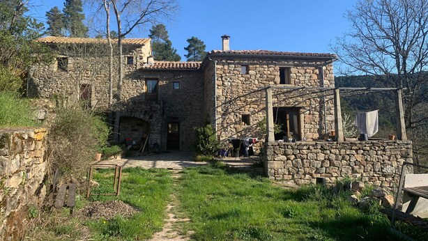 A stone building with a tiled roof, a wooden porch, and a dirt path leading to the entrance. - Self-contained, eco-renovated farmhouse in a small, unspoilt valley in the Cévennes. (Gagnières)