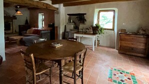 A rustic interior with a wooden dining table, chairs, and a tiled floor. - Self-contained, eco-renovated farmhouse in a small, unspoilt valley in the Cévennes. (Gagnières)