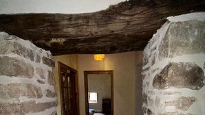 A narrow stone-walled hallway with wooden flooring leading to a room with a window and a door. - Self-contained, eco-renovated farmhouse in a small, unspoilt valley in the Cévennes. (Gagnières)