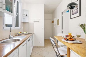 A modern kitchen with a sink, cabinets, and a dining area with a table set for breakfast.