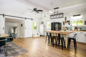 Una cocina con una isla central, taburetes de bar, un refrigerador y un ventilador de techo.