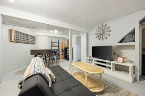 Una sala de estar con sofá, mesa de centro, televisor y un reloj de pared.