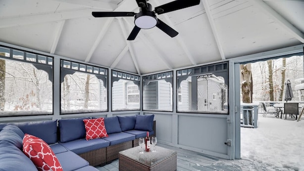 A covered patio with a blue sofa, a coffee table, and a ceiling fan.