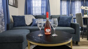 A living room with a sofa, two wine glasses, and a bottle of wine on a round table.