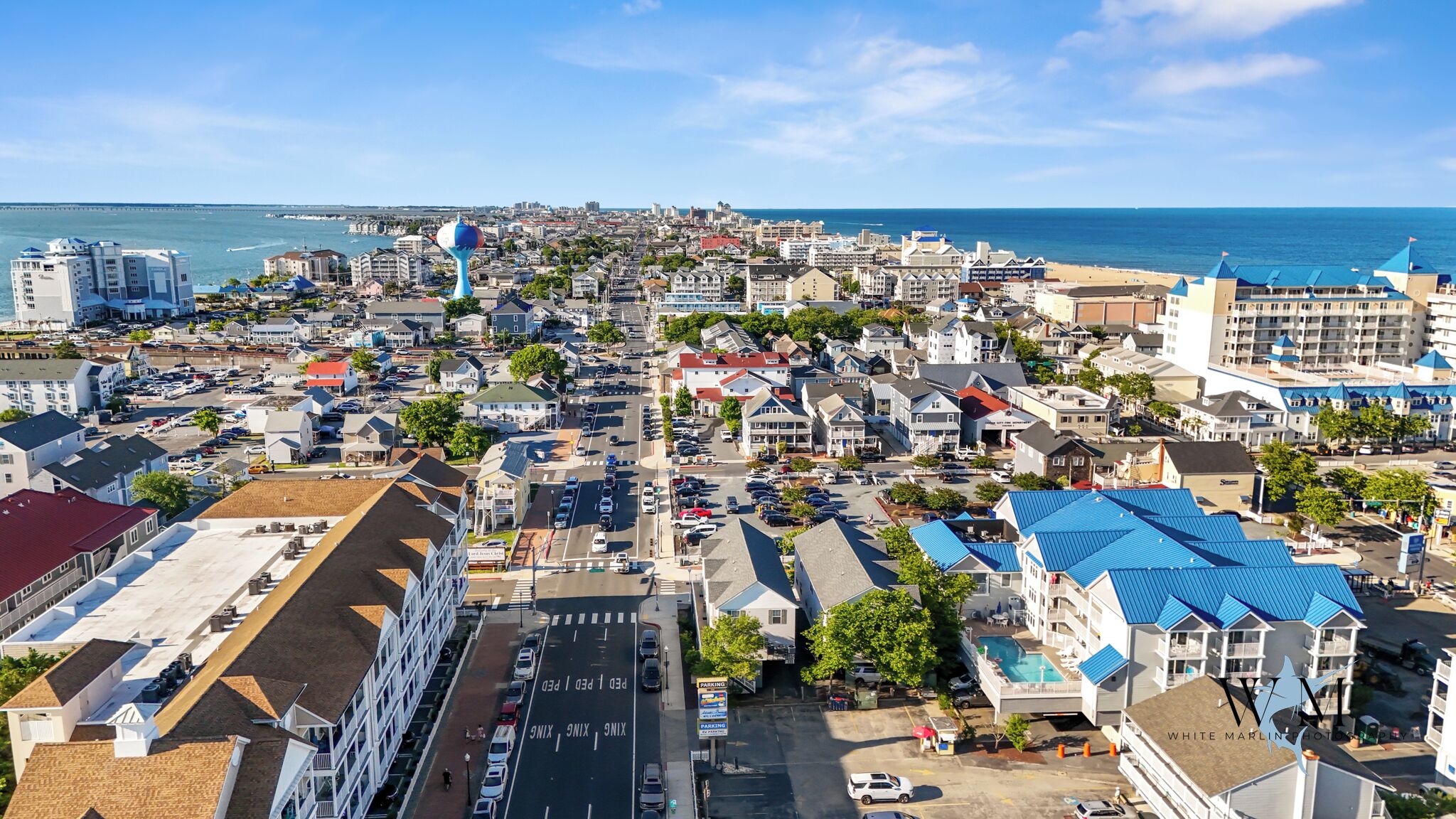 A coastal town with a mix of residential and commercial buildings, including a hotel with a blue roof and a swimming pool.