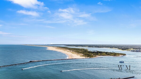 Eine Küstenlandschaft mit Sandstrand, einer Wellenbrecheranlage und einem Boot im Wasser.