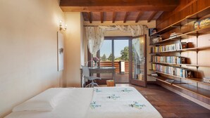 A bedroom with a bed, a desk, a bookshelf, and a view of the outdoors.