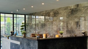 Un área de recepción moderna con mostrador de mármol, un sofá y elementos decorativos.