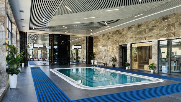 Una piscina interior de diseño moderno, rodeada de muros de piedra y plantas en macetas.