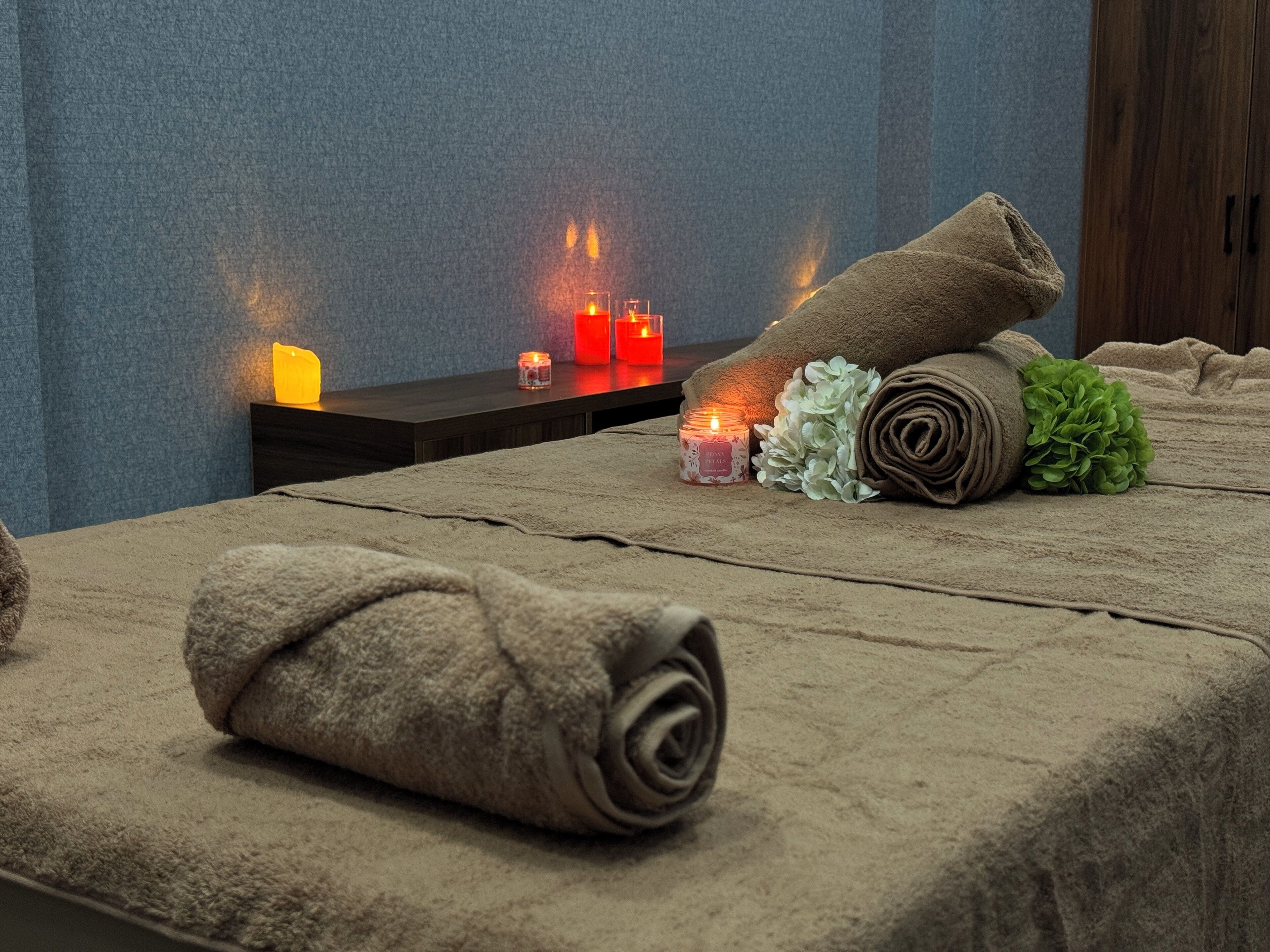 A neatly arranged spa area with a bed, towels, and candles.