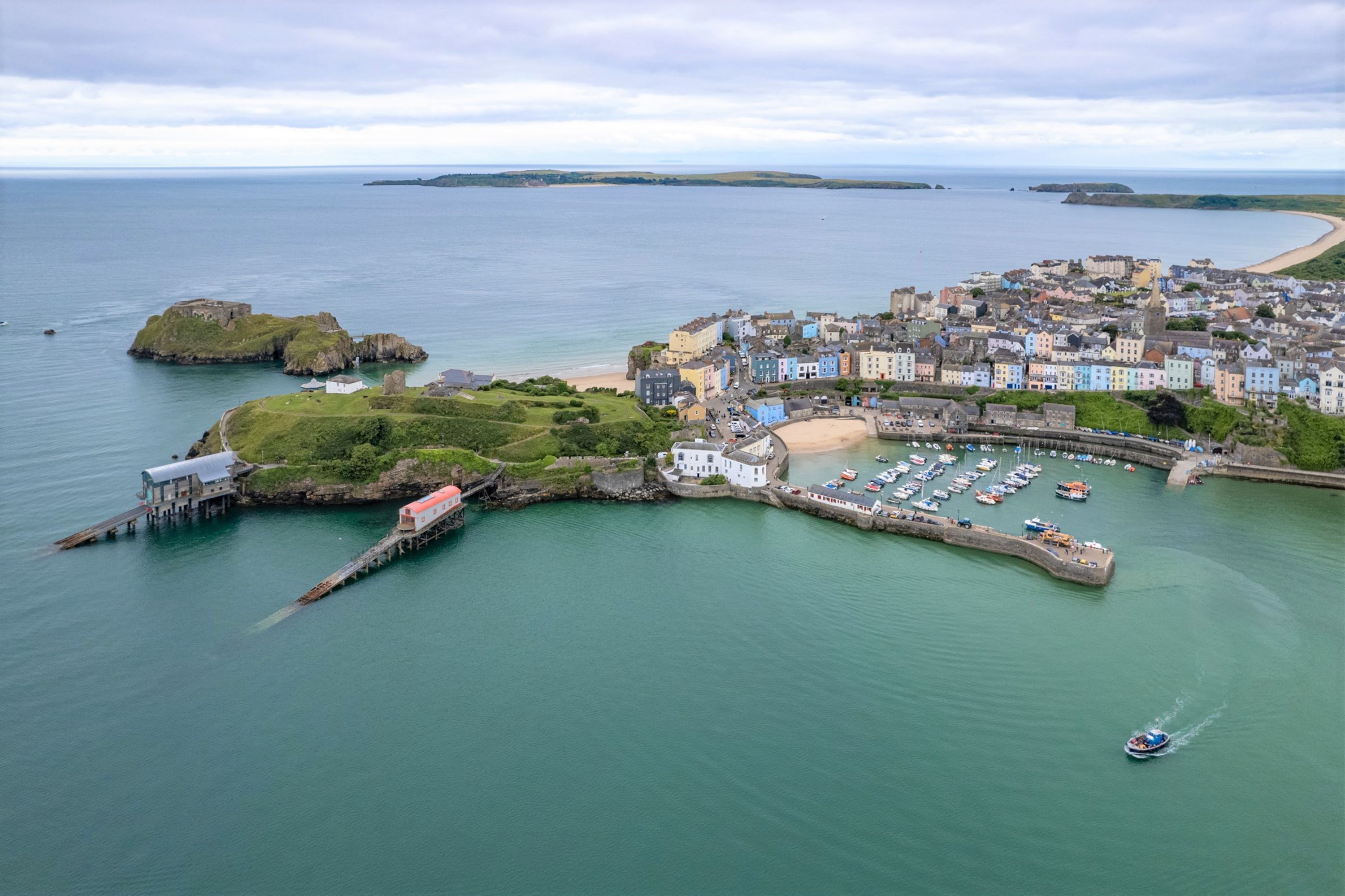 A coastal town with a marina, historic buildings, and a lighthouse.