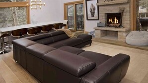 En moderne stue med en modulsofa, pejs og et spiseområde med barstole.