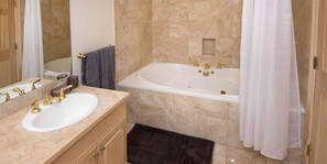 Une salle de bain avec une baignoire, un lavabo doté de robinets dorés et un miroir.